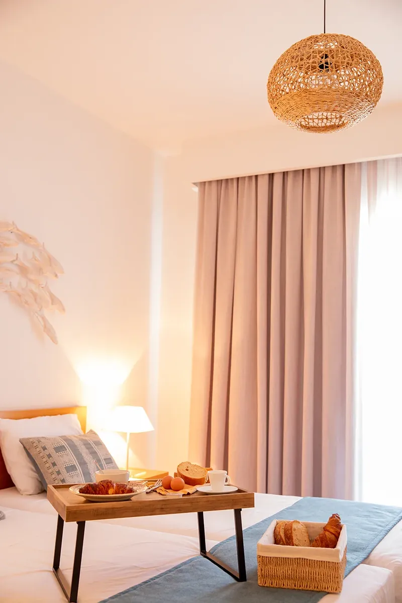 A breakfast tray by the bed, under a rattan lamp